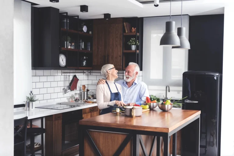 Lachend senior-stel kookt samen met verse groenten in hun eigen keuken