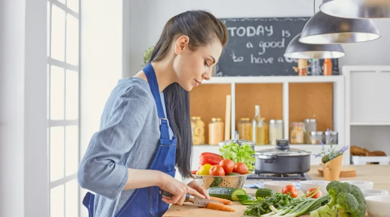 Jonge vrouw kookt een plantaardige maaltijd in haar eigen keuken