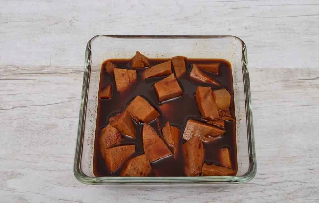 Blokjes gemarineerde tofu met sojasaus, knoflook en gember in een kom